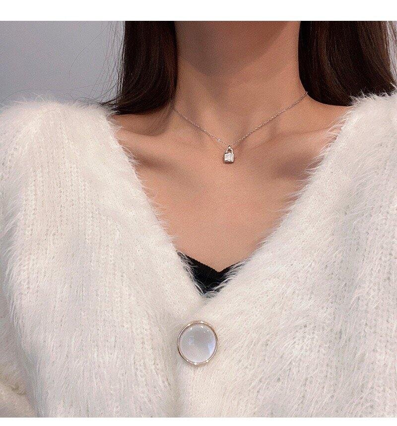 Woman wearing the Forever Close mother-of-pearl lock necklace