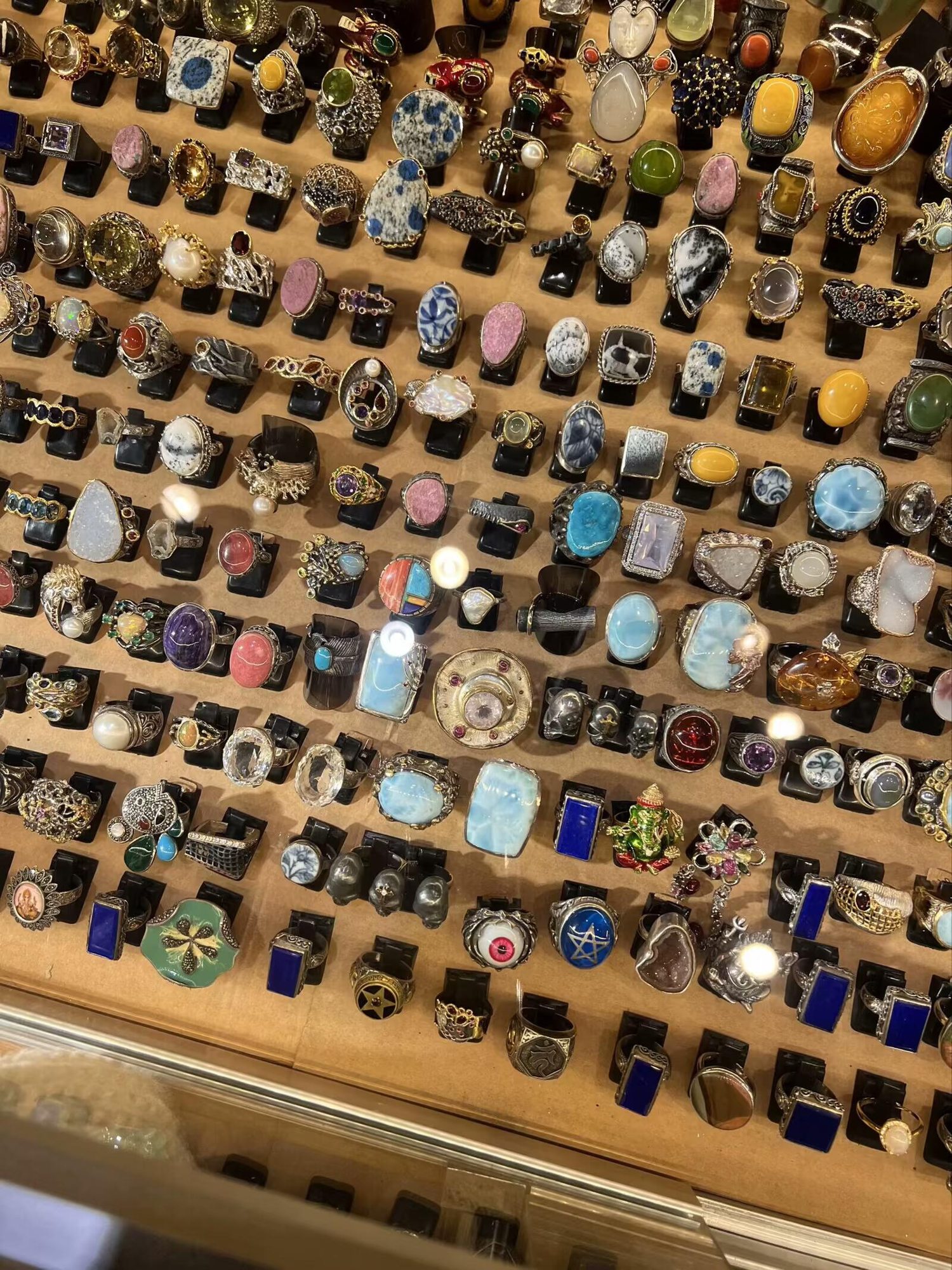 Assorted colorful gemstone-style rings displayed by a market vendor