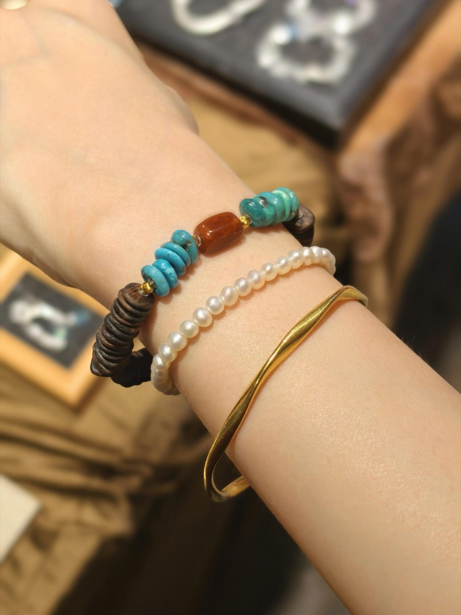 Layered pearl and turquoise-colored bead bracelets with a gold-tone bangle