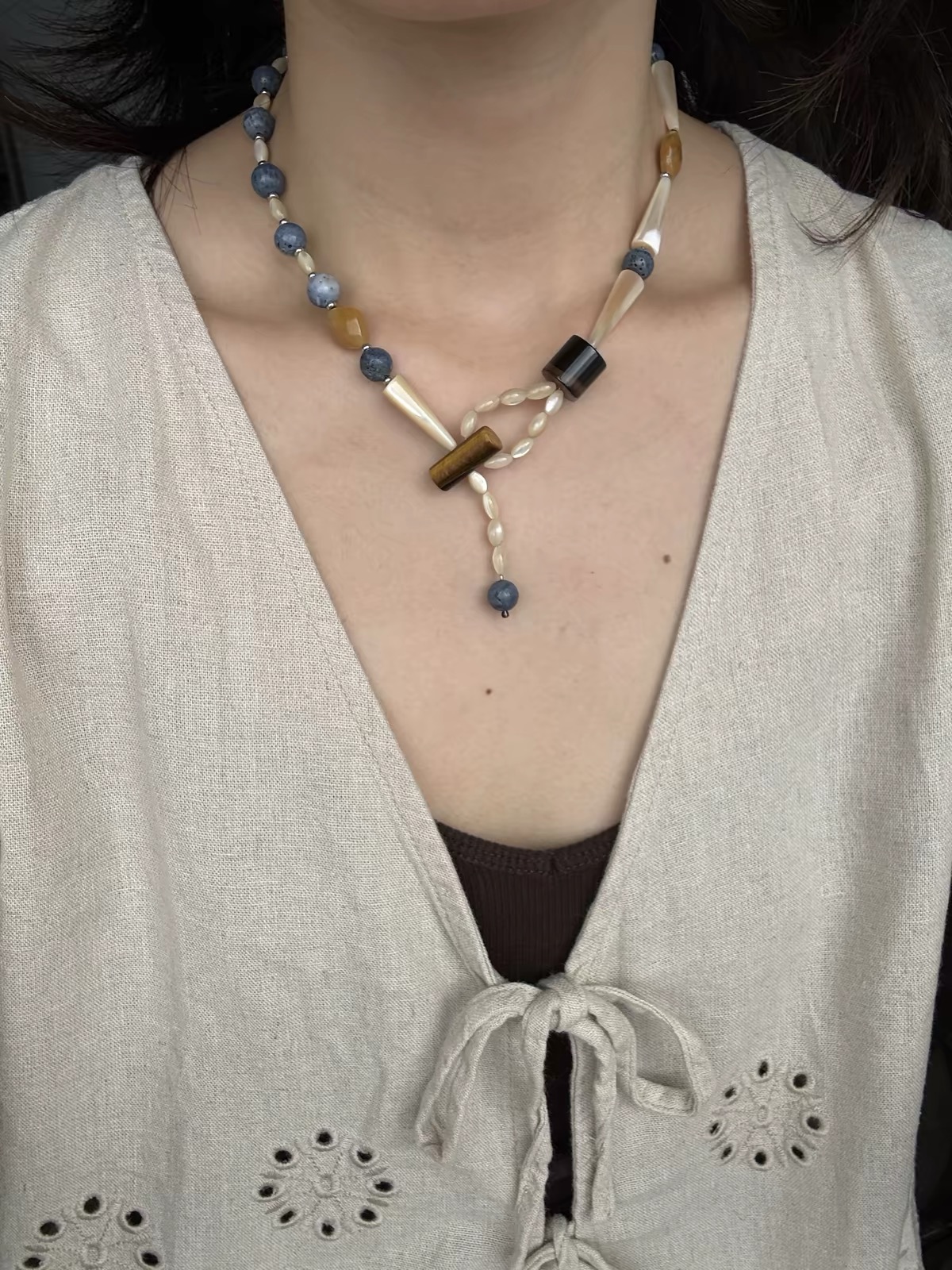 Asymmetrical blue and cream beaded necklace styled with a casual brown T-shirt.