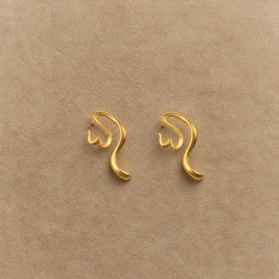 Pair of gold-plated 925 sterling silver earrings with open, curved calligraphy-inspired shapes.