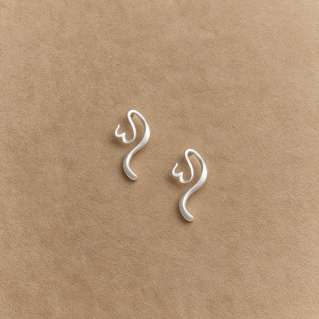 Pair of platinum-plated 925 sterling silver earrings with flowing sculptural curves on a beige background.