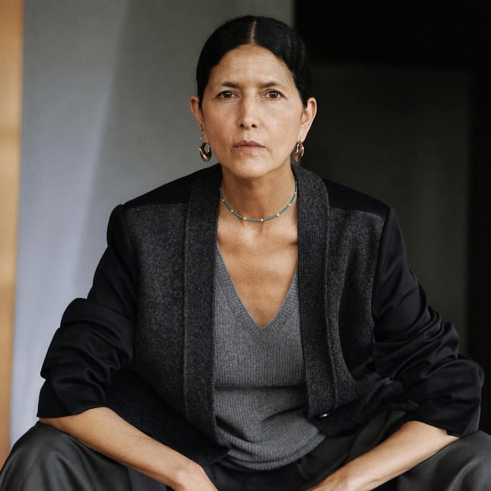 Woman wearing a delicate turquoise and pearl necklace with a dark blazer
