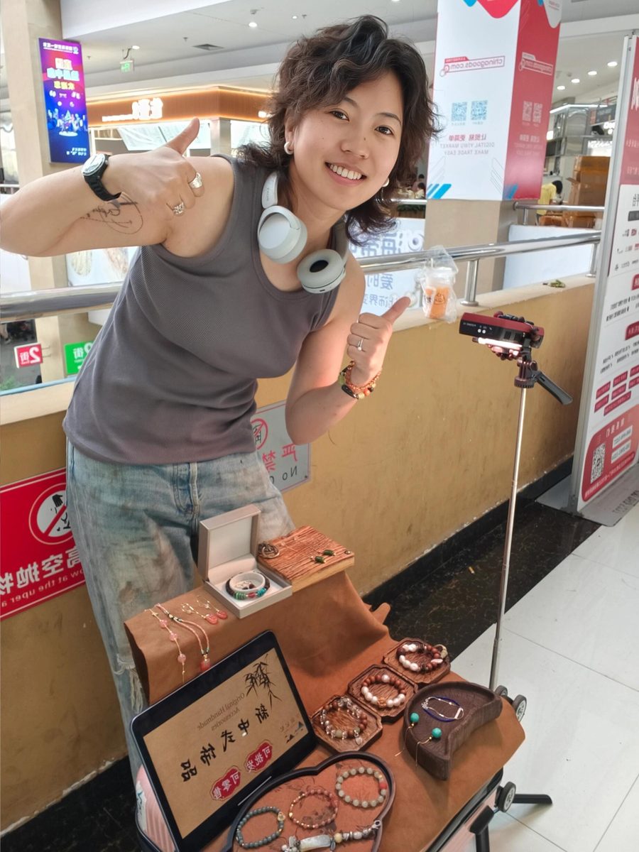 CJ at a small indoor market table with handmade bracelets and necklaces