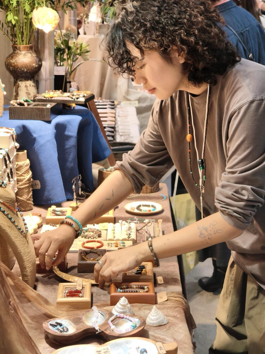 A maker arranging jewelry on the display table